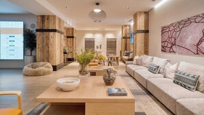 A modern living room with a wooden accent wall, a sofa set, a coffee table with decorative items, and a large abstract painting on the wall. - Alpine Oasis at Frontgate by Avantstay Luxe 3bdr Near Vail w/ Views Gym, Pool, Game Room (Avon)