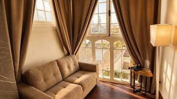 Una habitación con sofá, lámpara y vistas amplias a través de grandes ventanales.