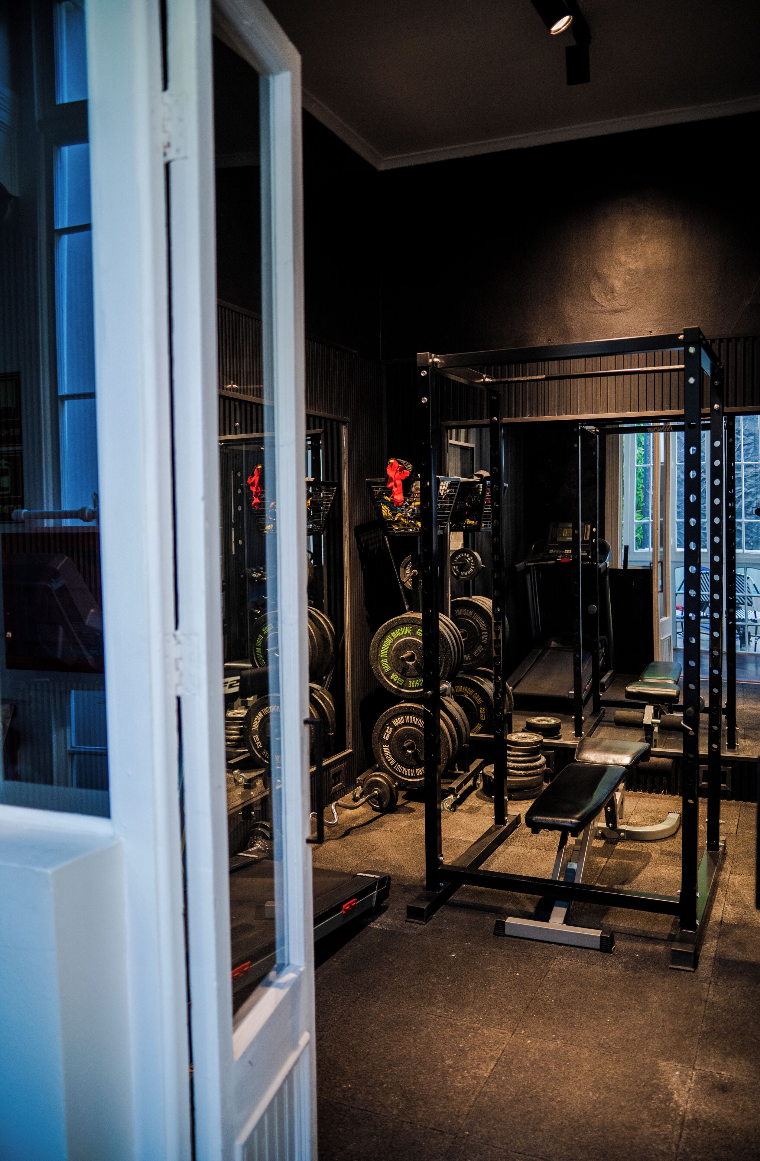 A gym with weightlifting equipment, a treadmill, and a bench.