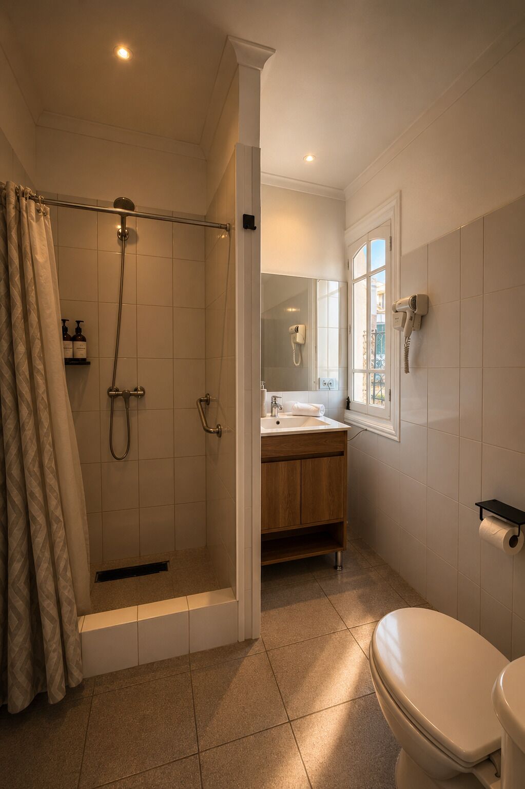 A bathroom with a shower, toilet, sink, and a window.