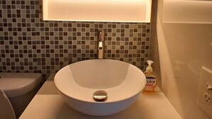 Un baño con un lavabo redondo, un espejo y un dispensador de jabón.
