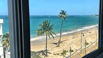A beach view with palm trees and a clear sky.