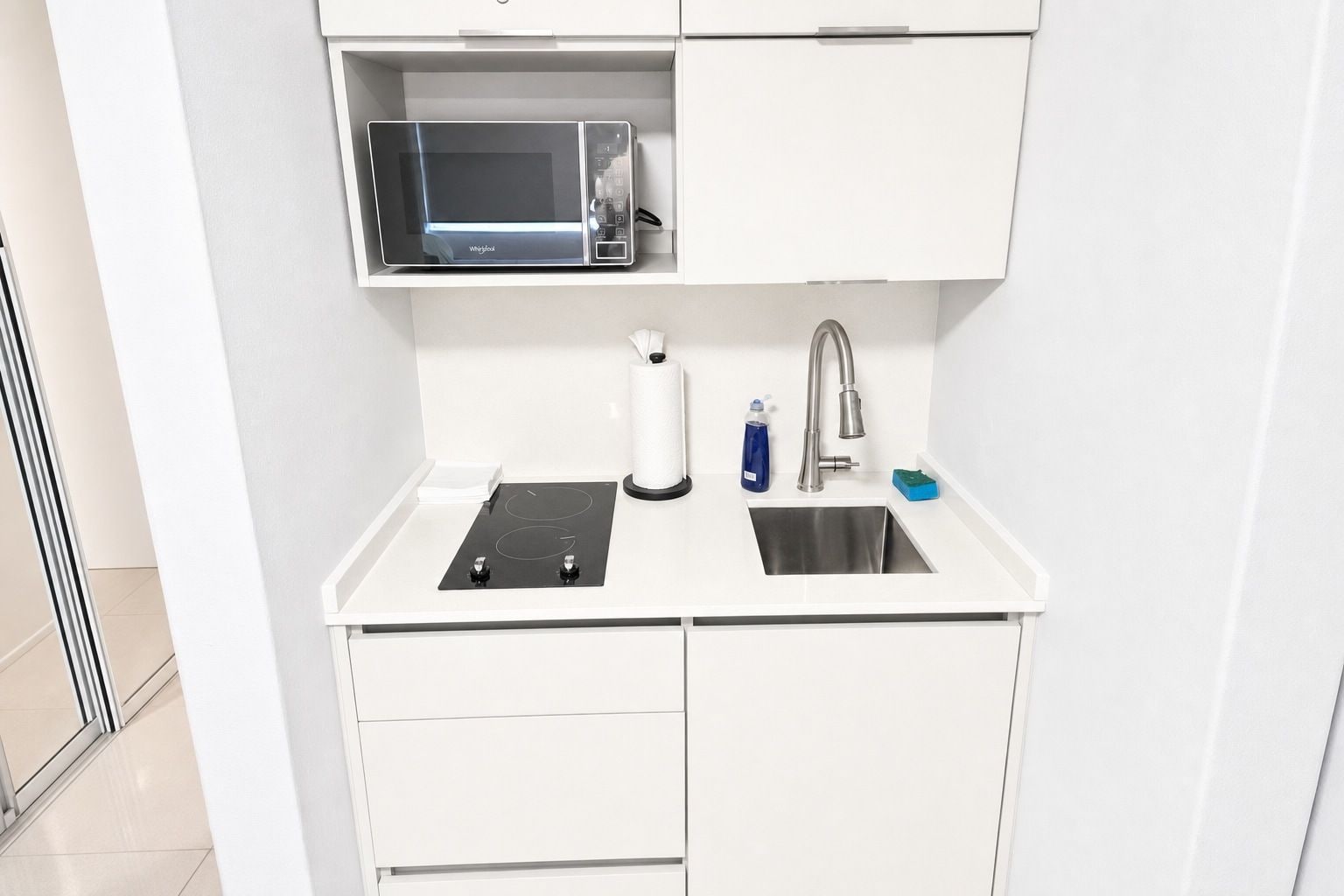 Une petite cuisine équipée comprenant un four à micro-ondes, un évier et un petit plan de travail.