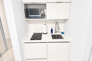 A compact kitchenette with a microwave, sink, and a small countertop.