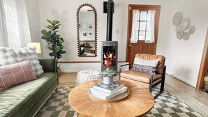 Ein gemütliches Wohnzimmer mit einem runden Holztisch, einem grünen Sofa, einem Ledersessel und einem Kamin.