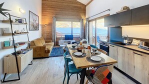 Una cocina moderna con techo de madera, zona de comedor con mesa para dos y vistas al exterior.