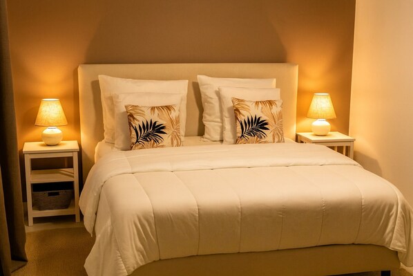 A neatly made bed with a white duvet and two pillows, flanked by two bedside tables with lamps, in a room with a warm, neutral color scheme. - Estate in Sologne with a pool!! (Selles-Saint-Denis)