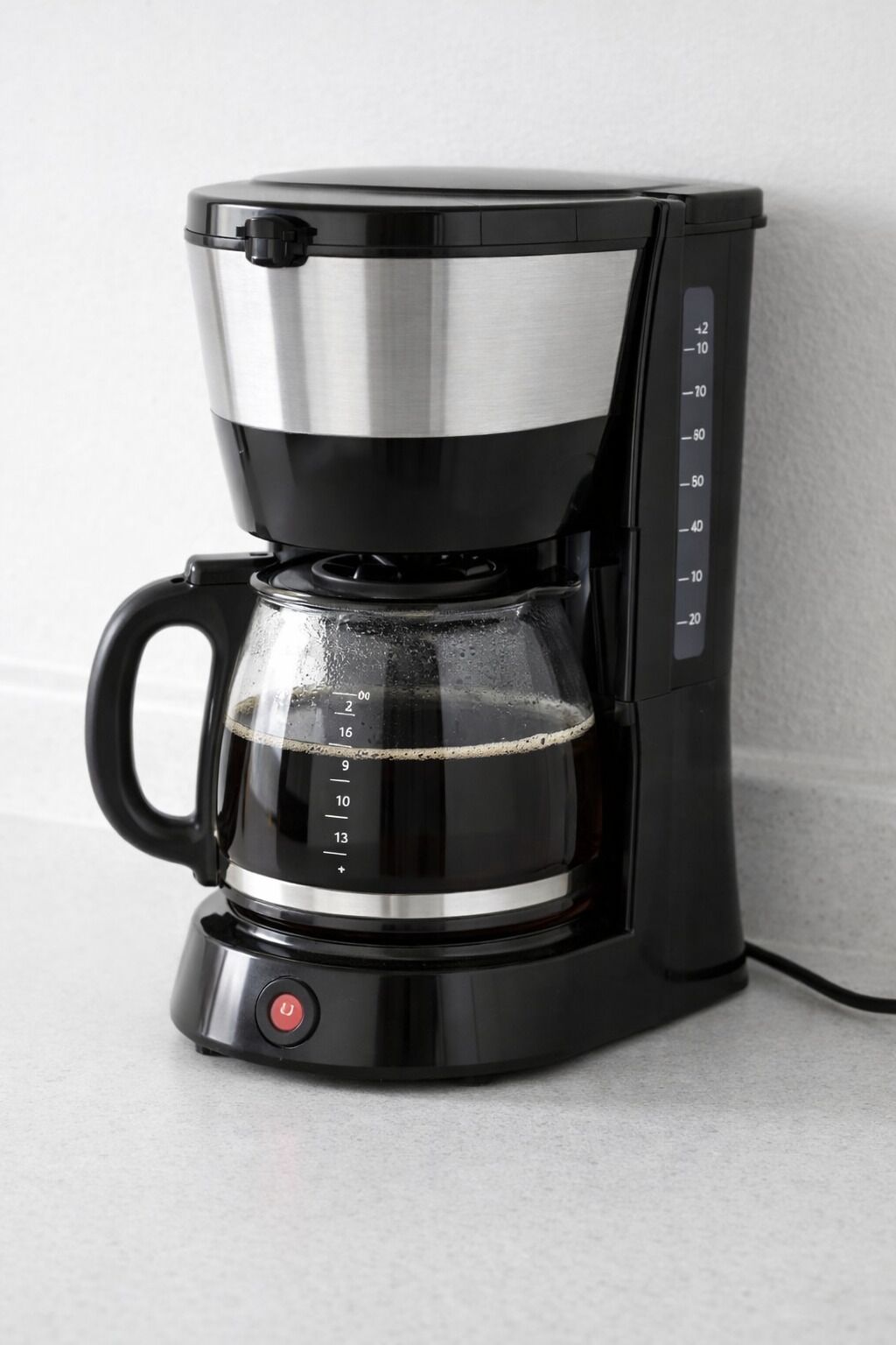 A black coffee maker with a transparent water reservoir and measurement markings.