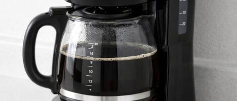 A black coffee maker with a transparent water reservoir and measurement markings.