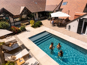 A swimming pool with lounge chairs and a dining area.