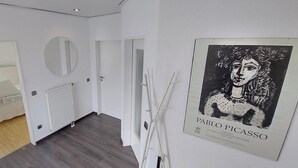 Ein modernes Interieur mit einem Bett, einem Heizkörper, einem Spiegel und einem Kunstdruck von Pablo Picasso.