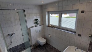 Ein modernes Badezimmer mit Duschkabine aus Glas, Toilette und Badewanne.