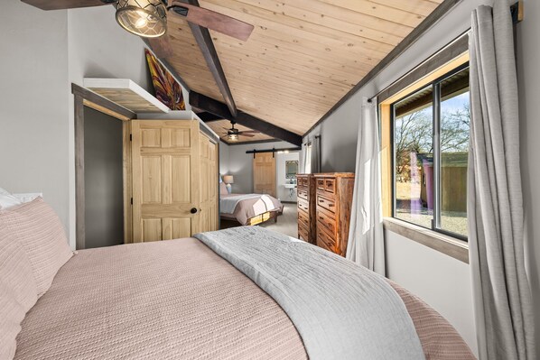 Quarto com cama grande, guarda-roupa de madeira e janela com cortinas.