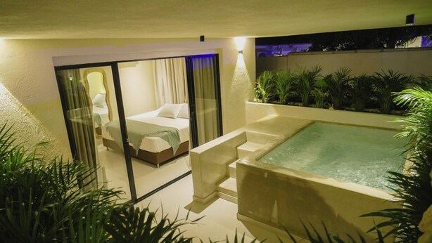 Ein modernes Schlafzimmer mit Glastür, eigenem Badezimmer und einer kleinen Outdoor-Jacuzzi-Anlage.