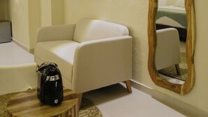 Ein modernes Wohnzimmer mit einer Couch, einem Couchtisch, einem Holznachttisch, einem an der Wand montierten Fernseher und einem großen Spiegel.