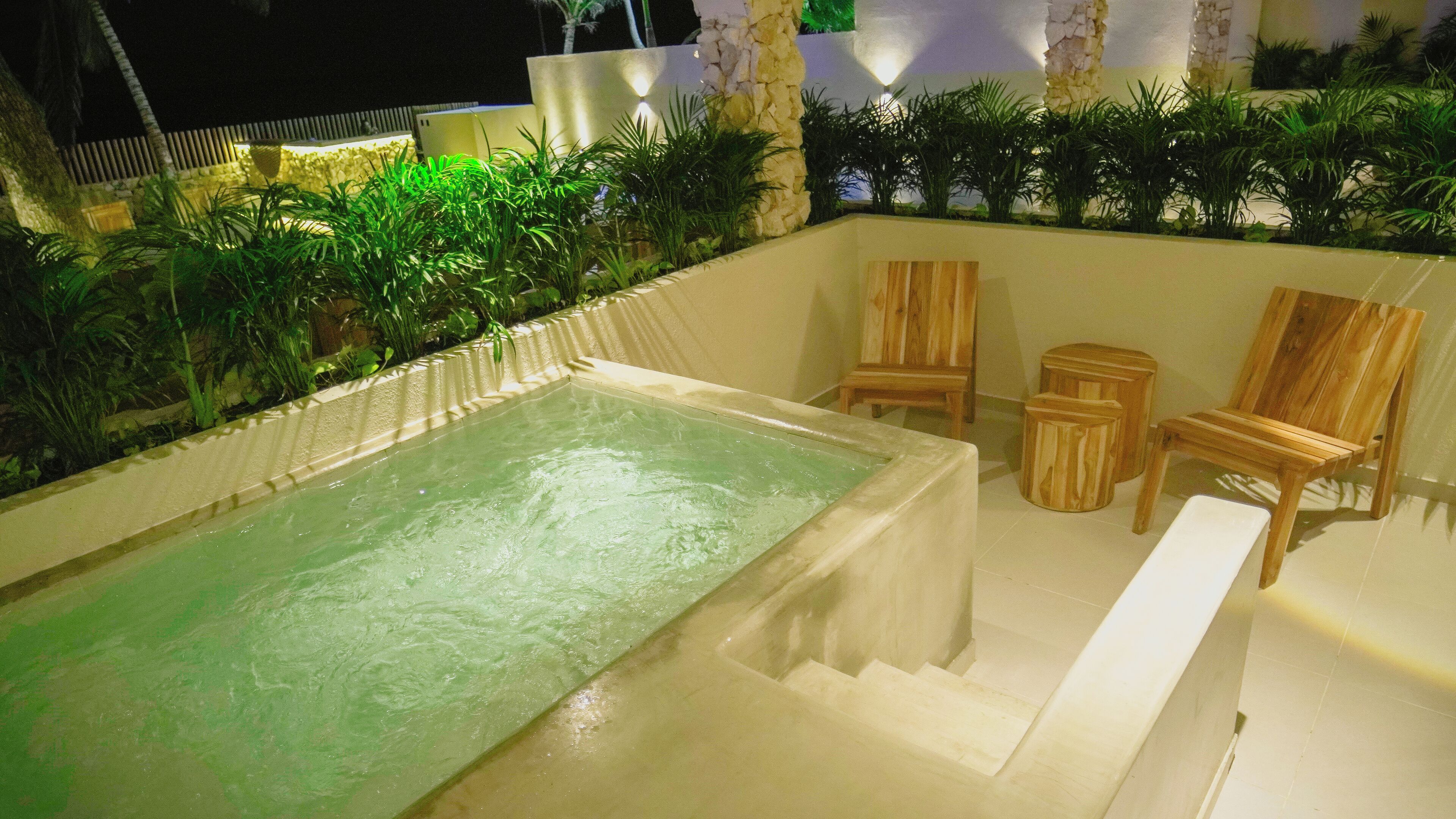 A spa area with a hot tub, wooden chairs, and a small table.