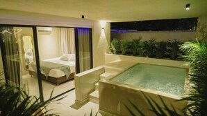 Ein modernes Schlafzimmer mit Glastür, die auf einen Balkon führt, einer großen Badewanne und Blick auf den Nachthimmel.