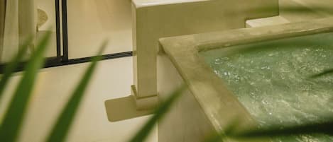 Een hotelkamer met een bed, een badkamer en een klein zwembad.