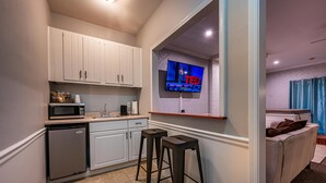 A compact kitchen with white cabinets, a microwave, a refrigerator, and a bar stool. - Luxury Hot tub Suite w/ In-Room Hot Tub & King Bed 1BR, 1BA (Nashville)