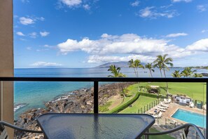 A balcony with a view of the ocean and a pool area.