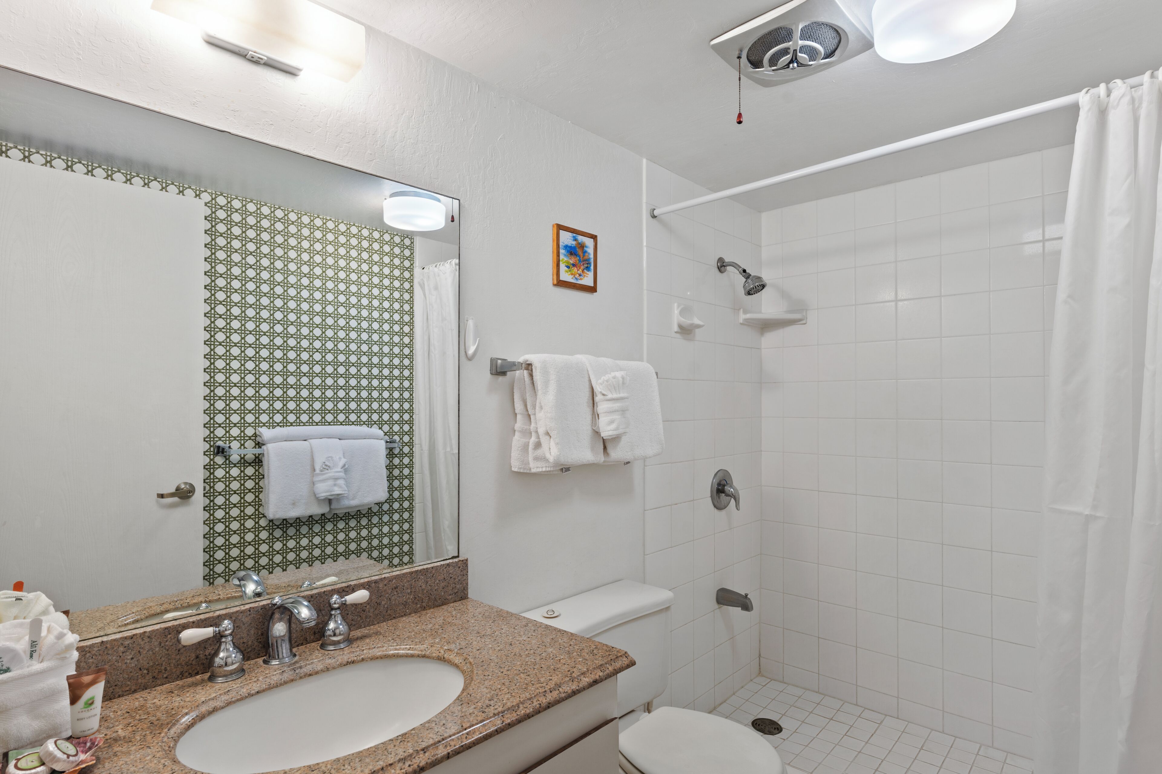 A bathroom with a sink, mirror, towel rack, shower, and toilet.