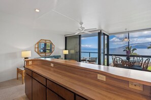 Eine moderne Küche mit Holztischplatte, Deckenventilator und Meerblick.