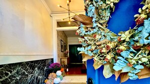 Een trap met decoratieve pompoenen en een blauwe deur met bloemdecoraties.