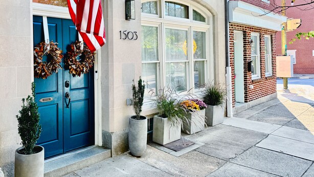 Een gebouw met een blauwe deur, een Amerikaanse vlag en huisnummer 1503.
