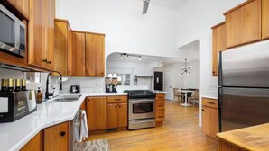 A modern kitchen with wooden cabinets, stainless steel appliances, and a central island. - Walk to the Big House, Sleeps 8, 4 bedrooms, 2 full bathrooms, 3 living rooms  (Ann Arbor)