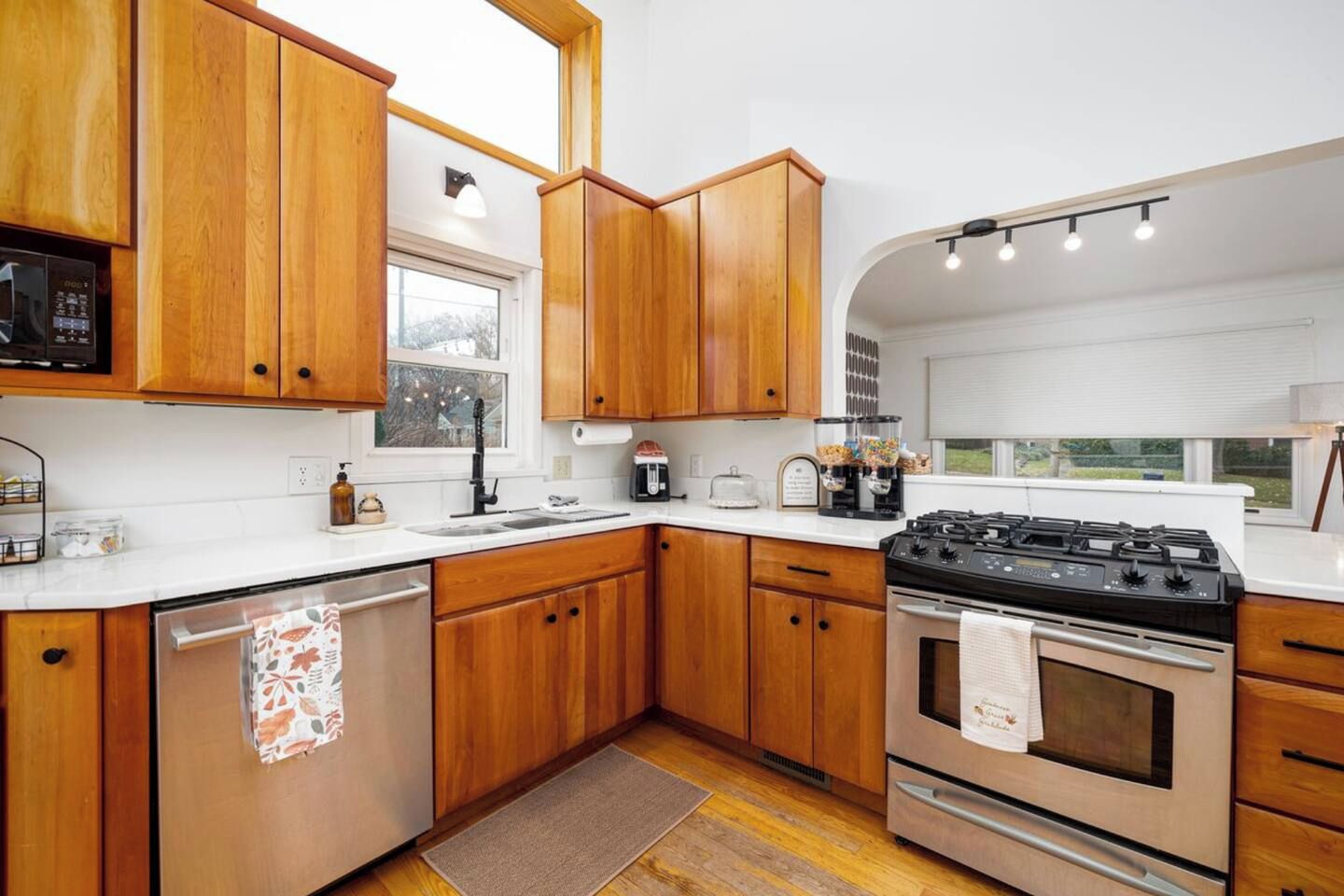 A modern kitchen with wooden cabinets, stainless steel appliances, and a large window providing natural light.