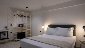 A modern bedroom with a bed, a wardrobe, and a desk with a lamp. - KEDL Junior Suites 101 (Kalamata)