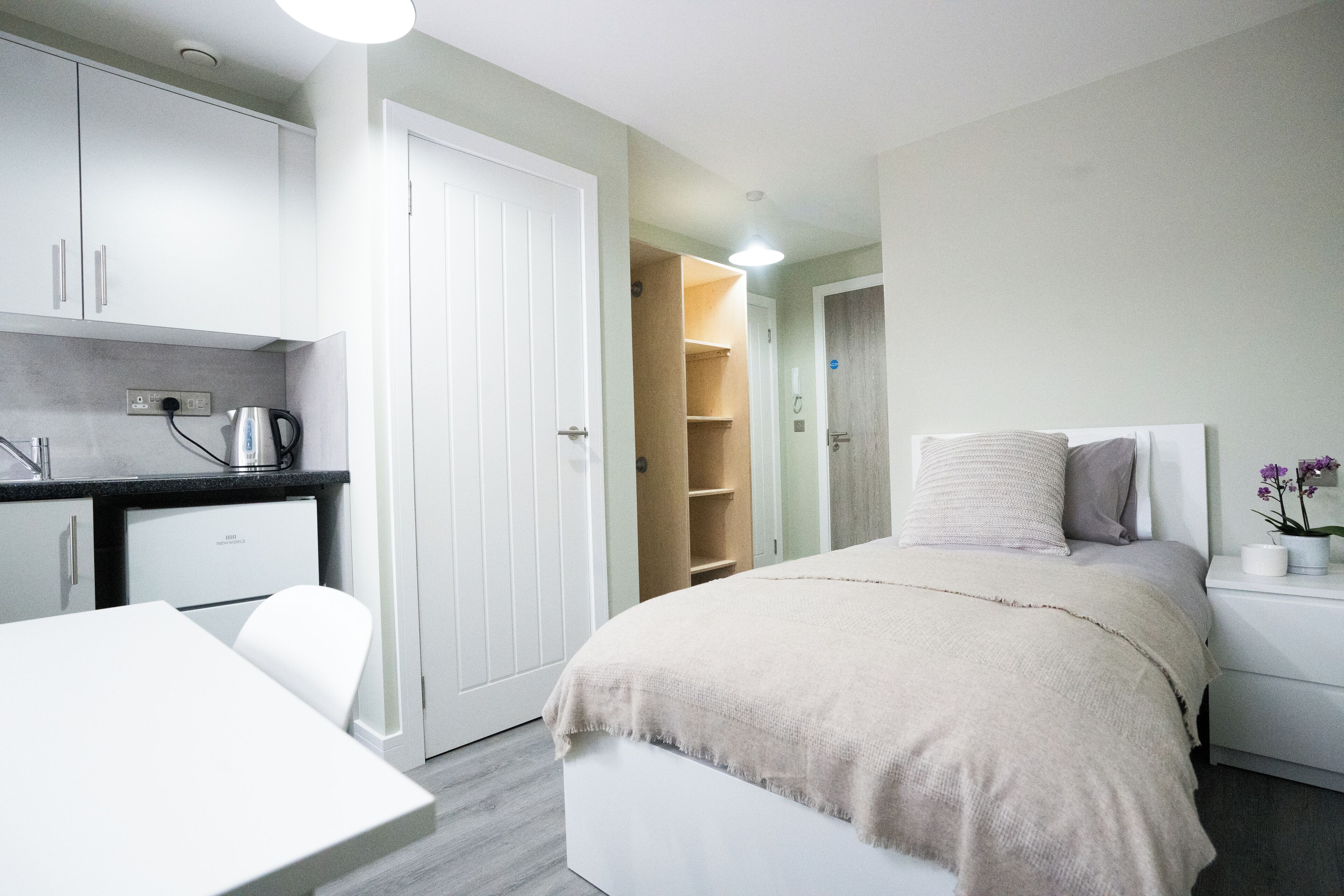 Een moderne slaapkamer met een bed, nachtkastje en een klein bureau.