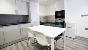 A modern kitchen with white cabinets, a black countertop, and a white dining table with blue chairs.
