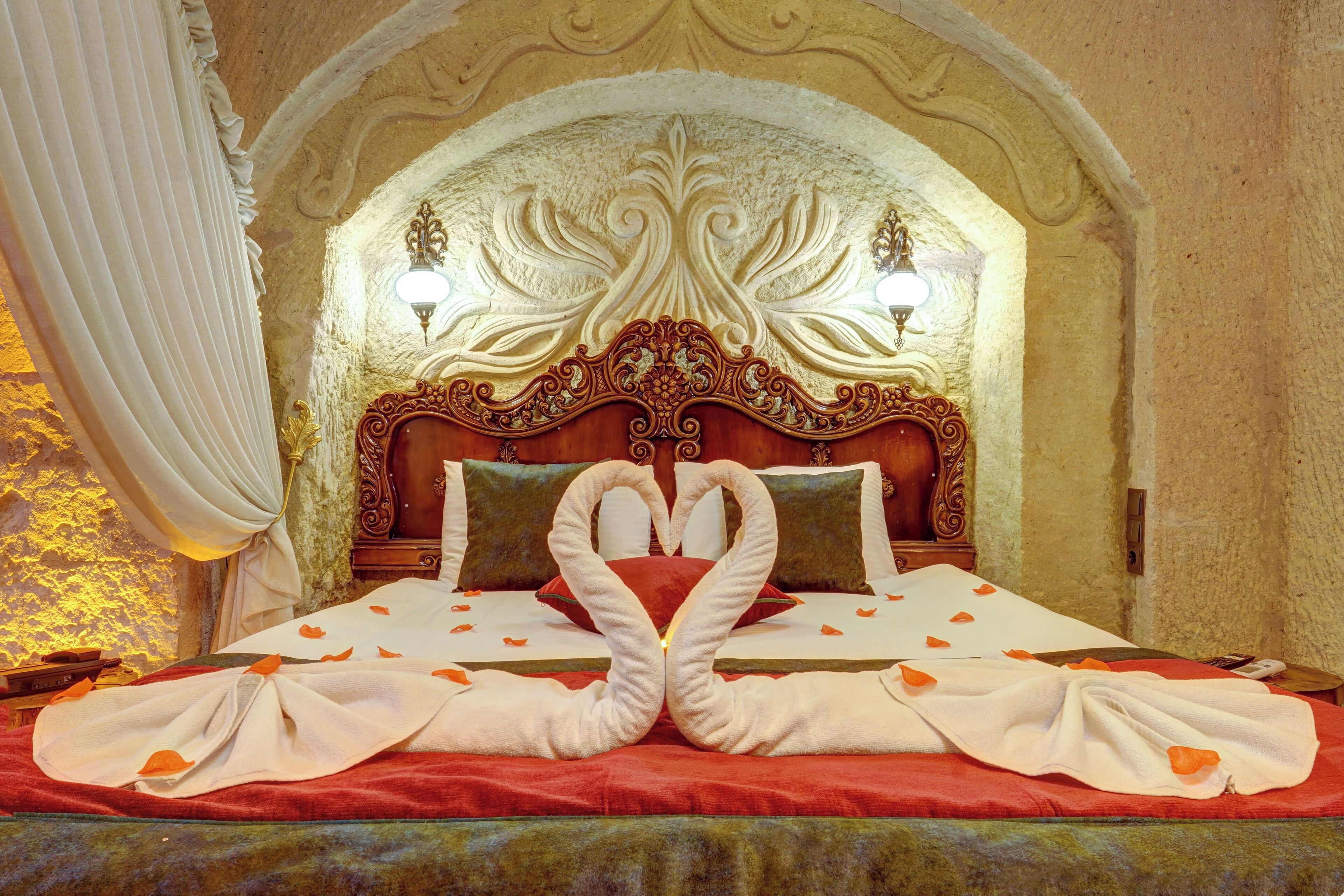 A luxurious bed with an ornate headboard, two wall-mounted lamps, and a decorative arch above.