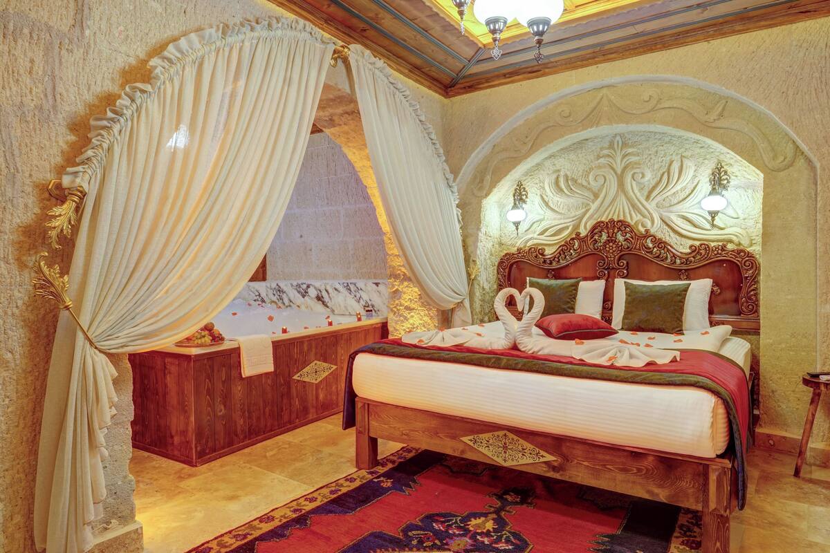 Un dormitorio lujoso con una cama grande, un cabecero ornamentado y un banco de madera.