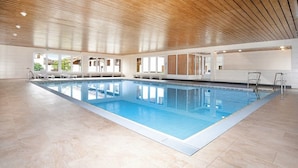 A large indoor swimming pool with clear blue water, surrounded by white walls and wooden ceiling beams. - FEWO in the vacation park Oberallgäu with gr. Pool, bed linen, towels, final cleaning (Missen-Wilhams)