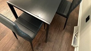 Ein moderner Essbereich mit einem rechteckigen Tisch, vier Stühlen, einem roten Sofa und einer Lampe im Hintergrund.