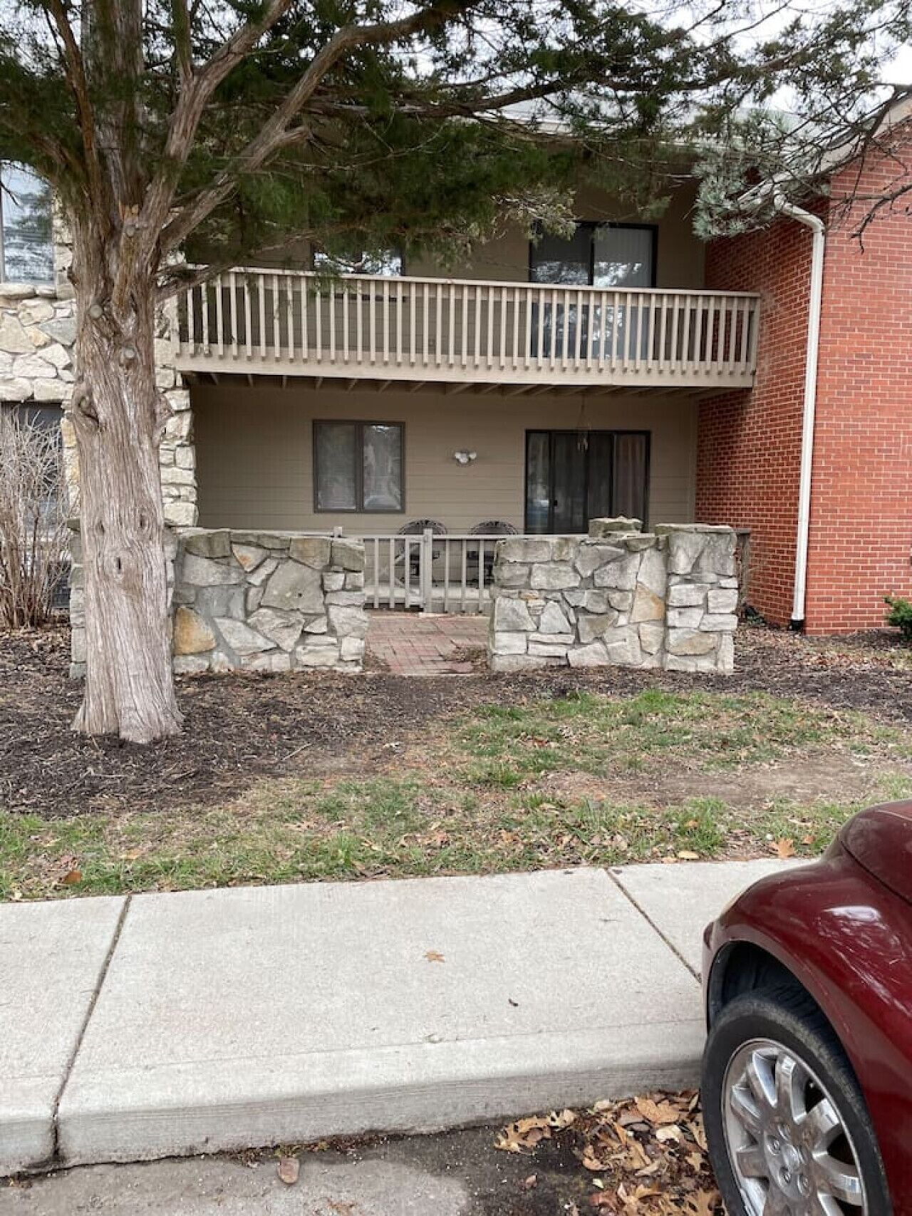 A two-story house with a stone facade, a balcony, and a driveway.