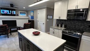 Une cuisine moderne dotée d’un îlot central, de meubles blancs, d’une cuisinière noire et d’un four à micro-ondes.