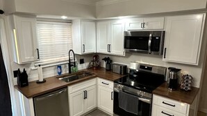 A modern kitchen with white cabinets, stainless steel appliances, and a wooden countertop. - 3 Bed 1.5 Bath Pet Friendly Apt (Columbia)