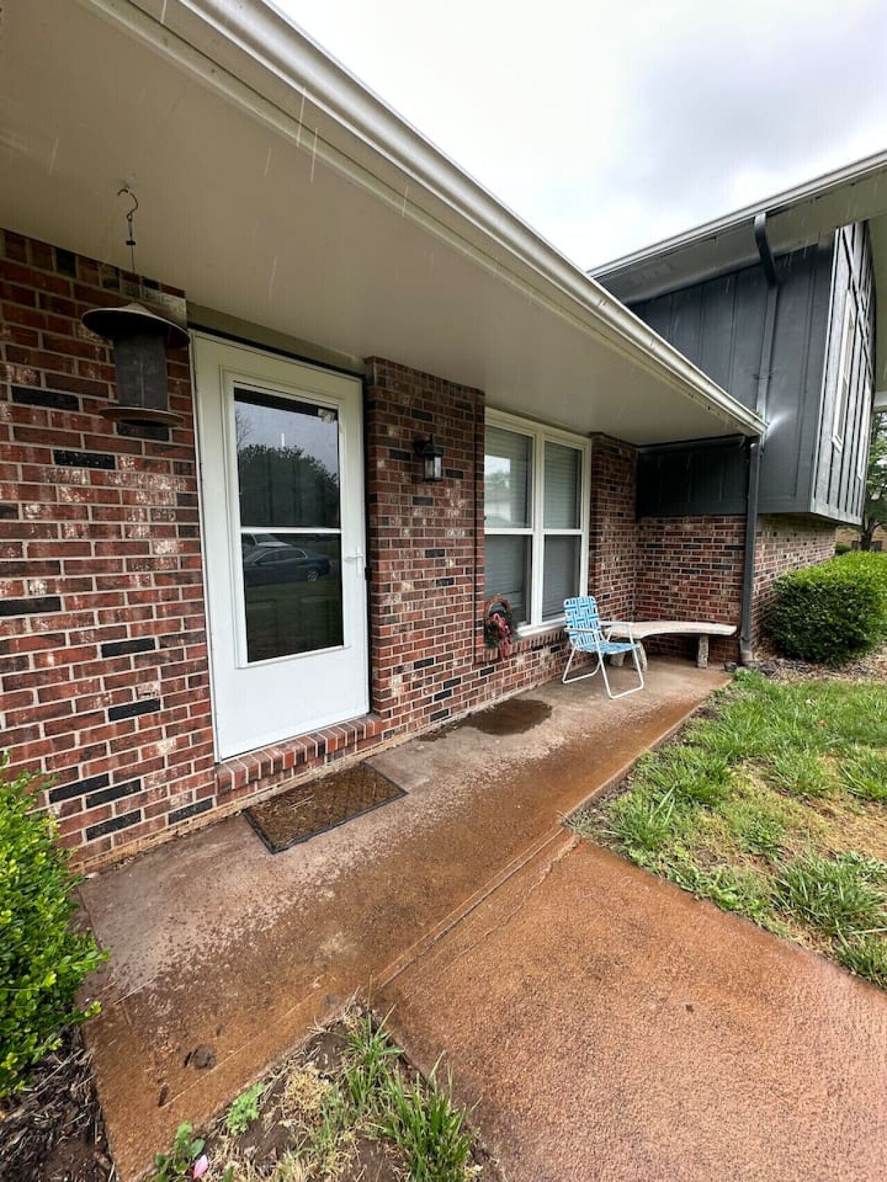 A single-story brick house with a covered porch, a front door, and a window.