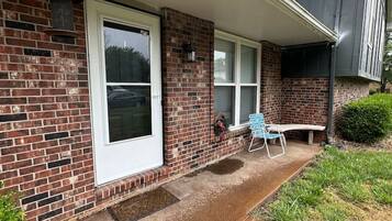 A single-story brick house with a covered porch, a front door, and a window.