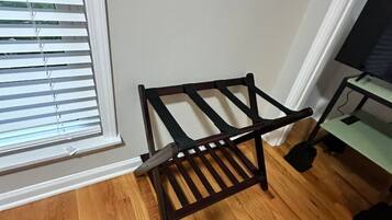 Een hoek van een kamer met een houten vloer, een zwart metalen rek en een televisietoestel op een standaard.