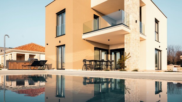 A modern two-story house with a swimming pool, a balcony, and a patio area with outdoor furniture. - Villa SUN Villa with pool and sea view (Labinci)
