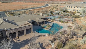 Un resort con piscina, un edificio grande y montañas al fondo.