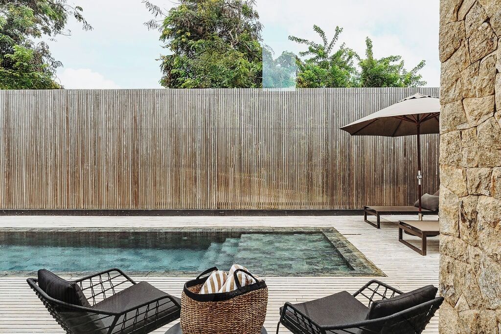 Una piscina al aire libre, sombrillas, sillones reclinables de piscina