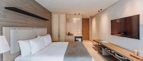 Een moderne hotelkamer met een groot bed, een aan de muur bevestigde televisie, een bureau en een zithoek met een bank.