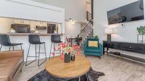 Un salon moderne avec une table basse ronde en bois, un canapé et un téléviseur fixé au mur.