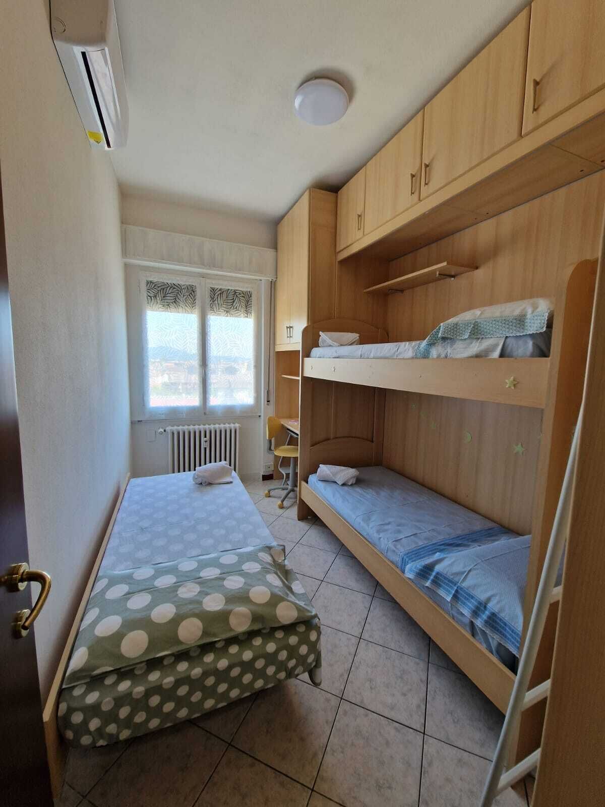 A compact room with bunk beds, a desk, and a radiator.