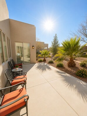 A patio with outdoor furniture, a palm tree, and a building with a glass door.